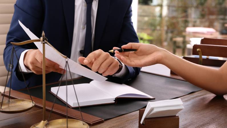 Car accident lawyer working with client at table in office, focus on hands