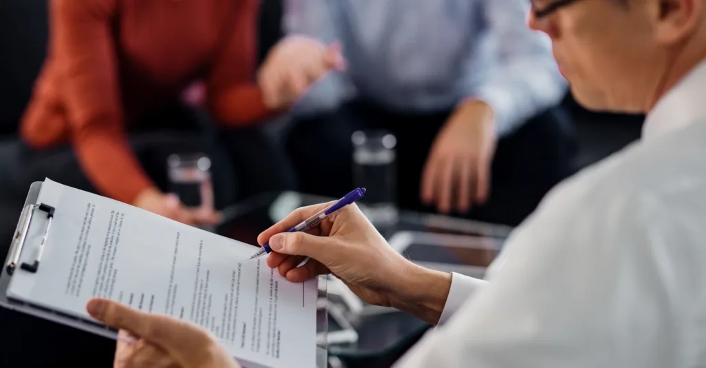 closeup_agent_going_through_lease_agreement_while_having_meeting_with_his_clients