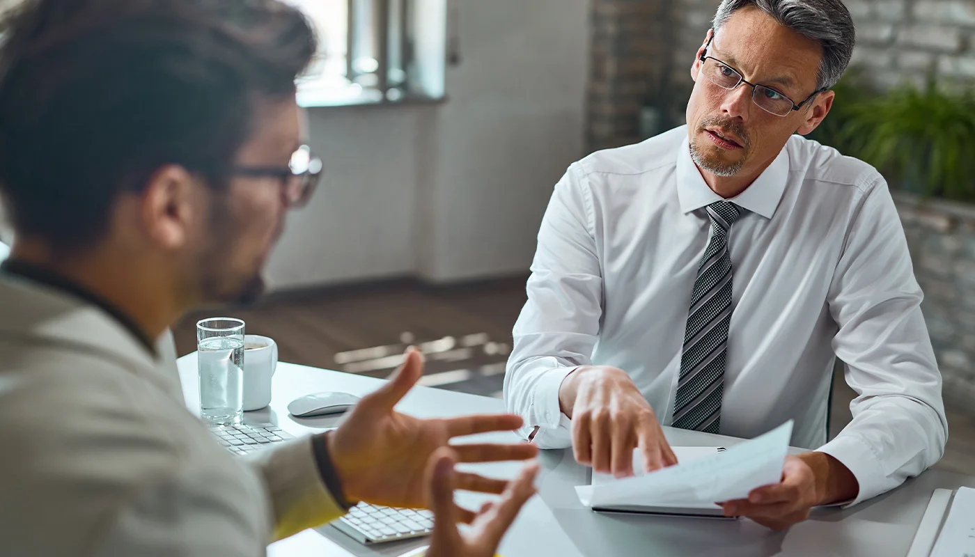Professional consultant explaining documents to client at an office desk