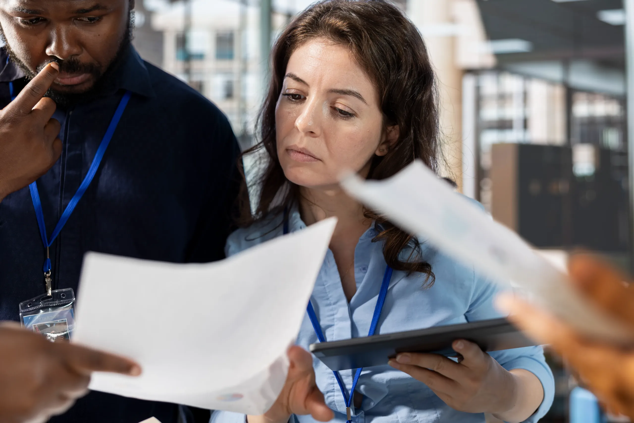 A woman holding a tablet while reviewing paperwork with her colleagues.